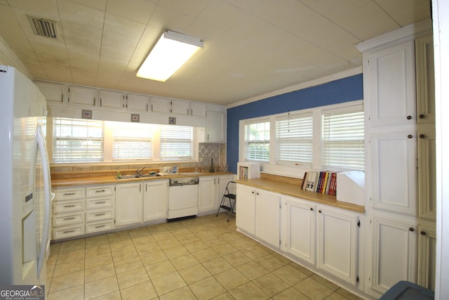 kitchen featuring white appliances, white cabinets, sink, decorative backsplash, and light tile patterned floors