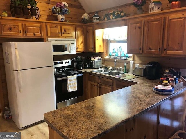 kitchen with light wood-type flooring, white appliances, wooden walls, sink, and lofted ceiling