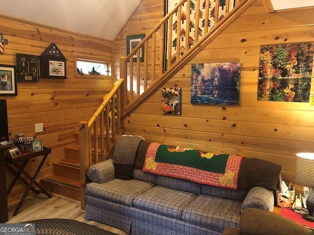 living room with wooden walls, wood-type flooring, and lofted ceiling