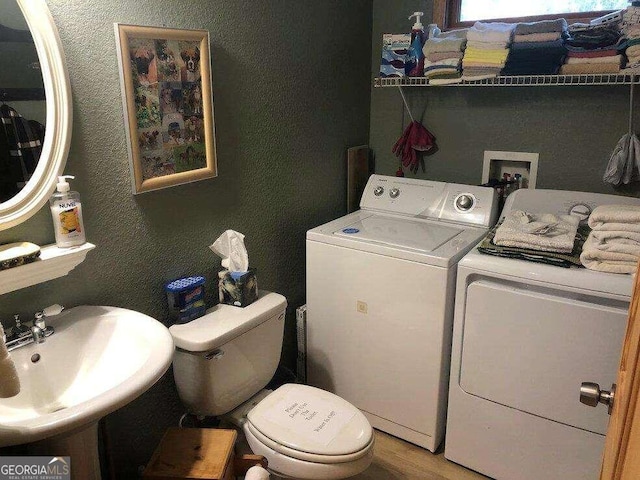 washroom with washing machine and dryer, sink, and wood-type flooring