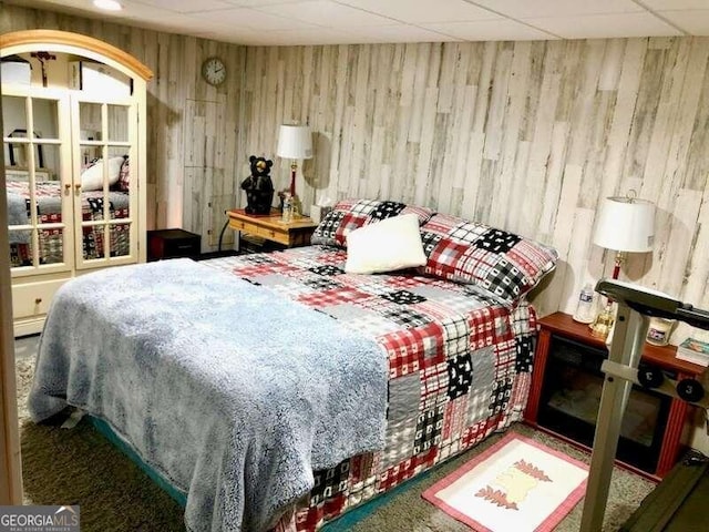 carpeted bedroom featuring a paneled ceiling and a baseboard heating unit