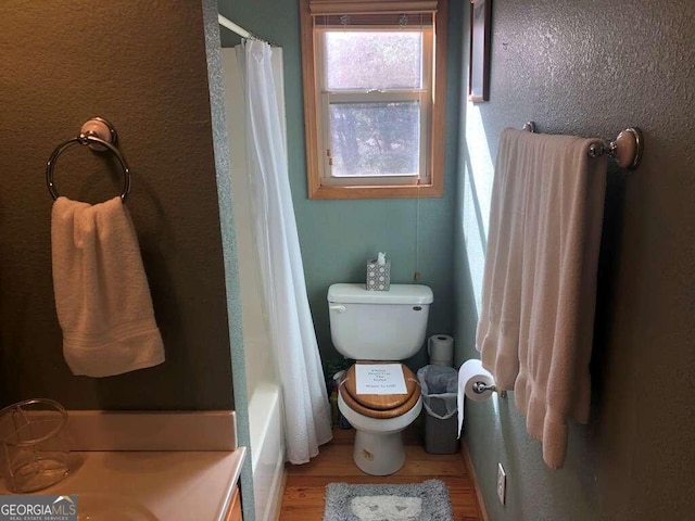 bathroom with toilet, shower / bathtub combination with curtain, and hardwood / wood-style flooring