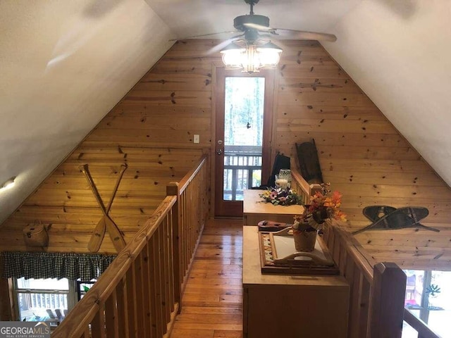 additional living space with hardwood / wood-style floors, ceiling fan, lofted ceiling, and wood walls