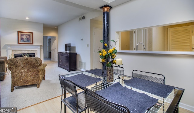 dining area with light wood-style flooring, a fireplace, visible vents, and baseboards