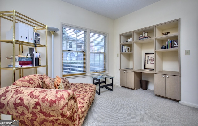 sitting room with baseboards, built in study area, and carpet flooring