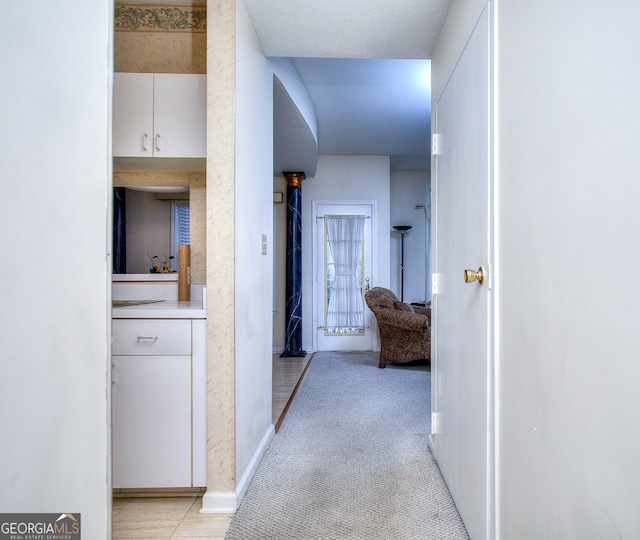 corridor with light tile patterned floors and a textured ceiling