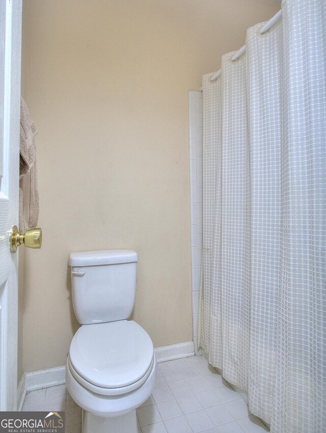 bathroom with a shower with shower curtain, tile patterned flooring, toilet, and baseboards