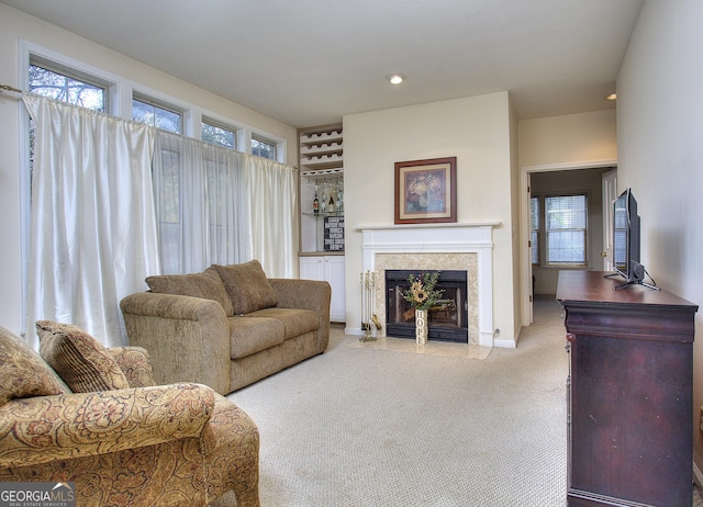 living area with carpet, a fireplace with flush hearth, and a healthy amount of sunlight