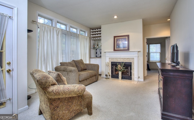 carpeted living area featuring a fireplace with flush hearth, recessed lighting, and baseboards