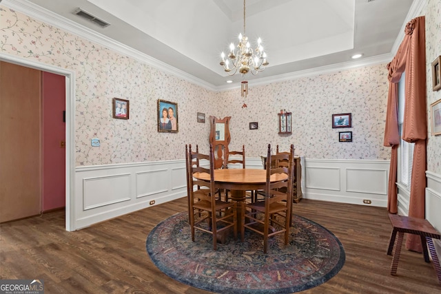 dining room with a raised ceiling, ornamental molding, dark wood-type flooring, and a notable chandelier