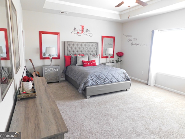 bedroom with carpet floors, a tray ceiling, and ceiling fan