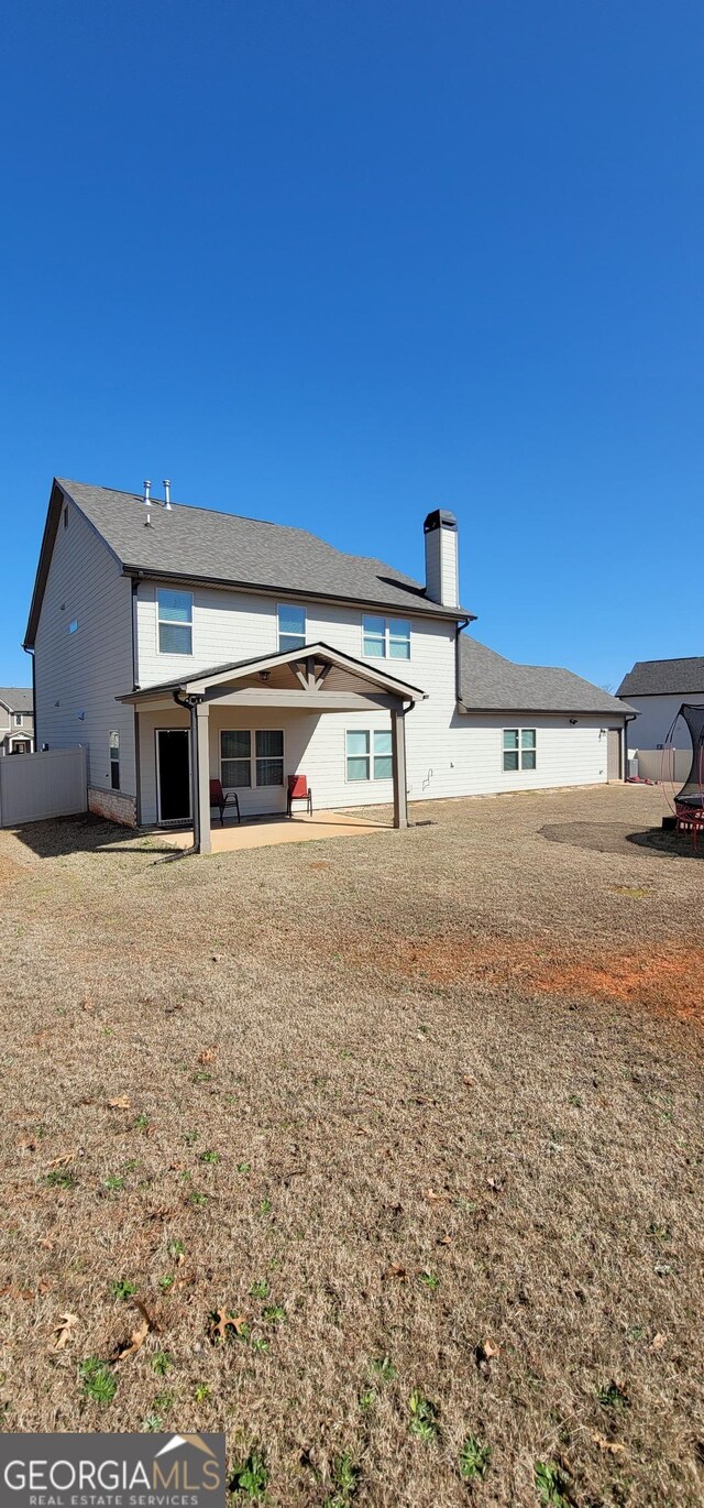 rear view of house with a lawn and a patio