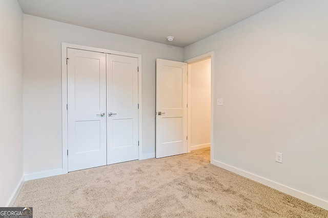 unfurnished bedroom with light carpet and a closet