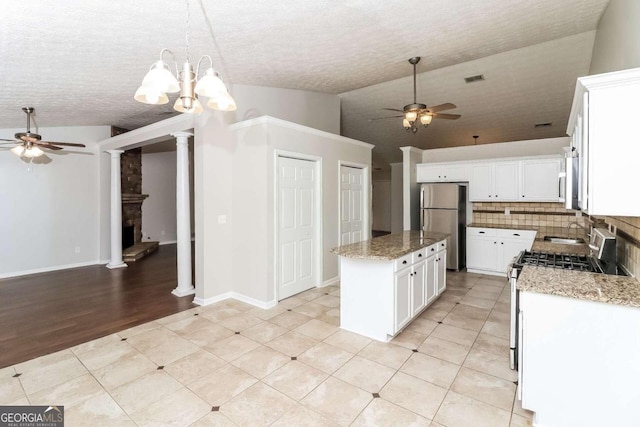 kitchen featuring light stone countertops, a center island, pendant lighting, white cabinets, and appliances with stainless steel finishes