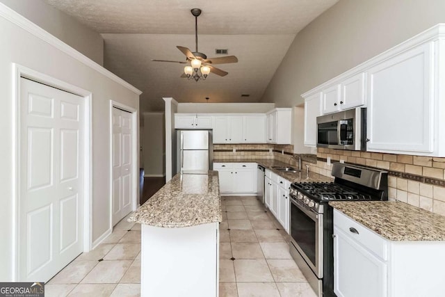 kitchen with a kitchen island, stainless steel appliances, white cabinetry, and lofted ceiling