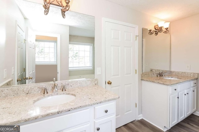 bathroom with a notable chandelier, wood-type flooring, a textured ceiling, and vanity