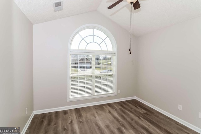 empty room featuring a textured ceiling, lofted ceiling, ceiling fan, and dark wood-type flooring