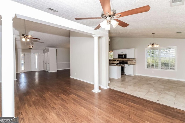 unfurnished living room featuring a textured ceiling, hardwood / wood-style floors, ceiling fan with notable chandelier, and lofted ceiling