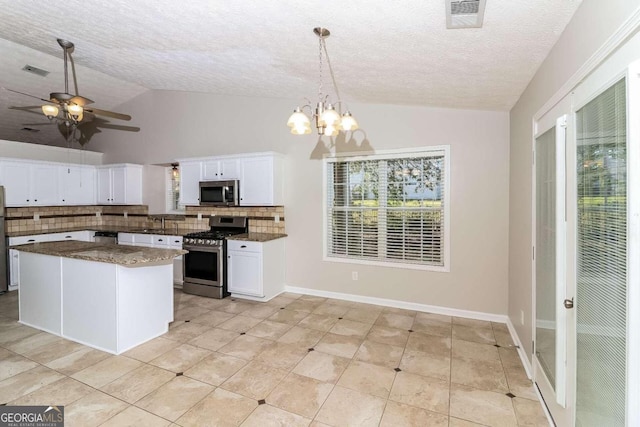 kitchen featuring decorative backsplash, a textured ceiling, stainless steel appliances, white cabinetry, and hanging light fixtures