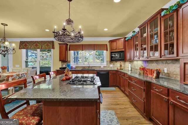 kitchen featuring a breakfast bar, a wealth of natural light, ornamental molding, and black appliances