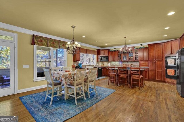 dining space featuring hardwood / wood-style flooring, plenty of natural light, ornamental molding, and an inviting chandelier