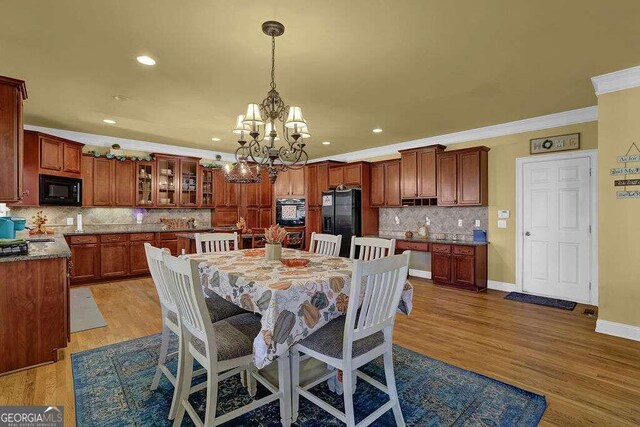 dining area with wood-type flooring, crown molding, and a notable chandelier