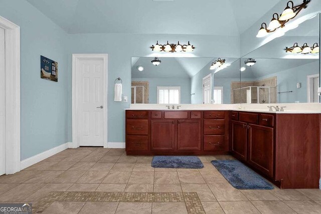 bathroom with tile patterned flooring, vanity, vaulted ceiling, and a shower with shower door