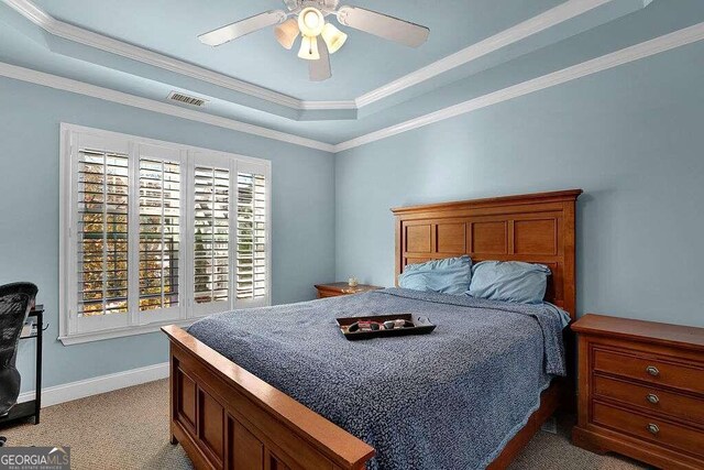 bedroom featuring light colored carpet, a raised ceiling, ceiling fan, and ornamental molding