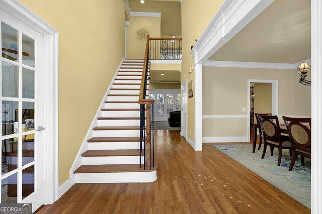 stairway featuring hardwood / wood-style floors, a wall unit AC, french doors, and crown molding