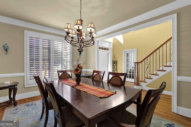 dining space with hardwood / wood-style flooring, an inviting chandelier, and ornamental molding