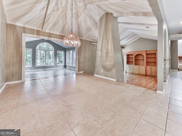 interior space featuring tile patterned flooring, vaulted ceiling with beams, wooden walls, and an inviting chandelier