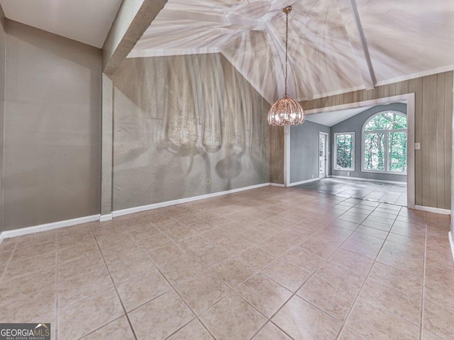 unfurnished room featuring tile patterned floors, a notable chandelier, lofted ceiling, and wooden walls