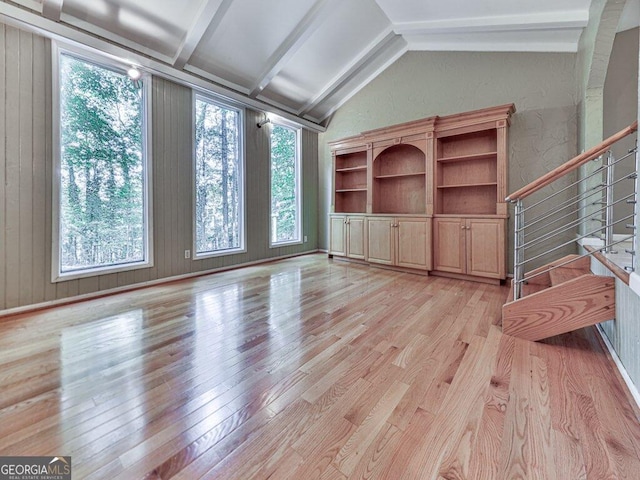 unfurnished living room featuring wooden walls, light hardwood / wood-style flooring, and a healthy amount of sunlight