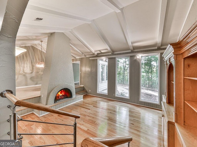 living room featuring a notable chandelier, vaulted ceiling with beams, light wood-type flooring, and a fireplace