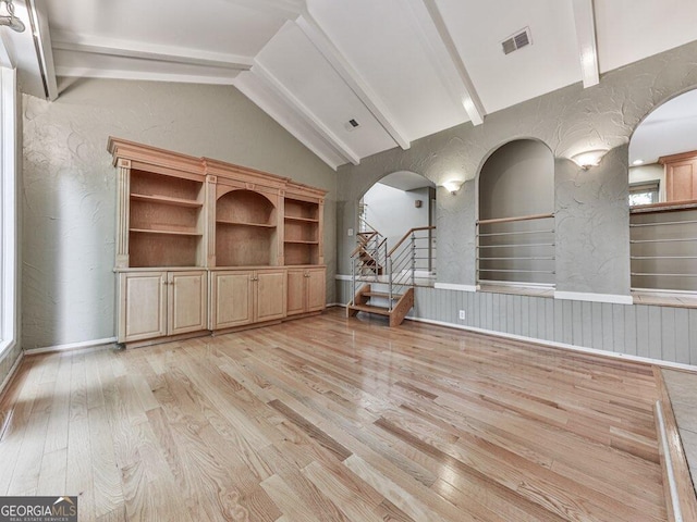 unfurnished living room with lofted ceiling with beams and light hardwood / wood-style floors