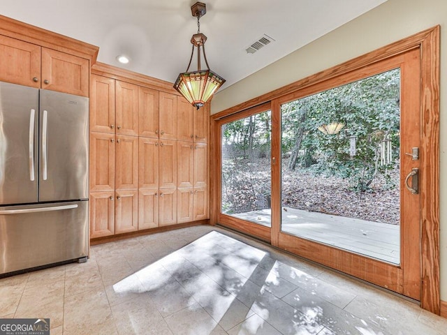 kitchen with stainless steel fridge, light brown cabinets, and decorative light fixtures