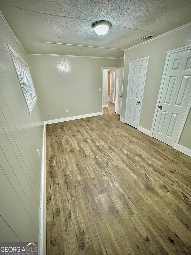 spare room with hardwood / wood-style floors, a textured ceiling, and wooden walls