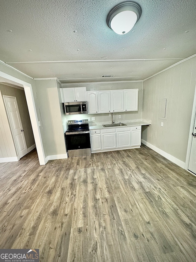 kitchen with appliances with stainless steel finishes, a textured ceiling, sink, light hardwood / wood-style flooring, and white cabinets