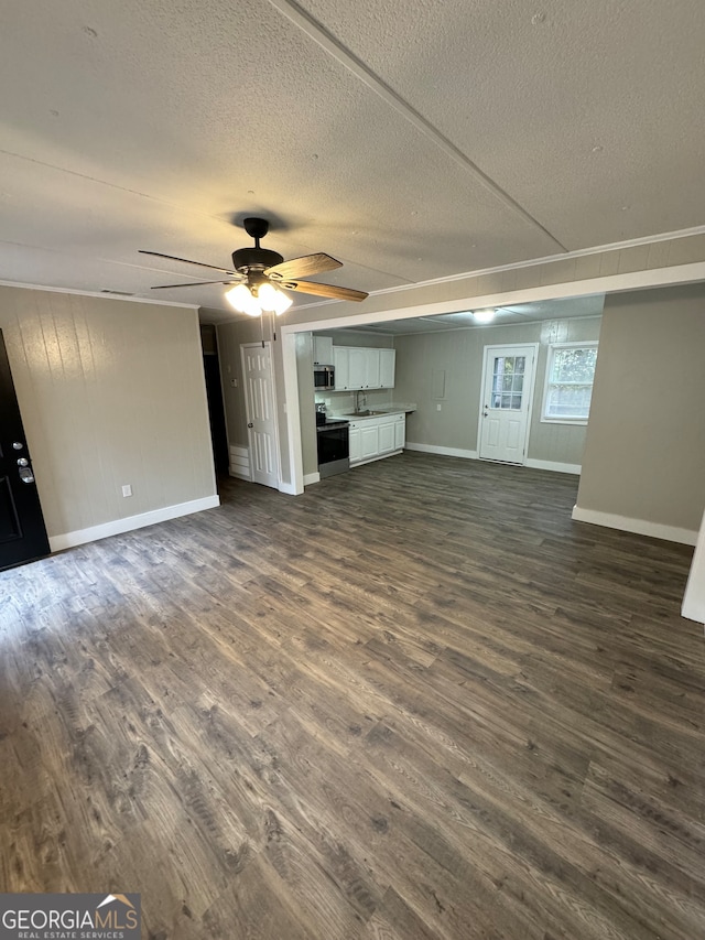 unfurnished living room with a textured ceiling, ceiling fan, sink, and dark wood-type flooring