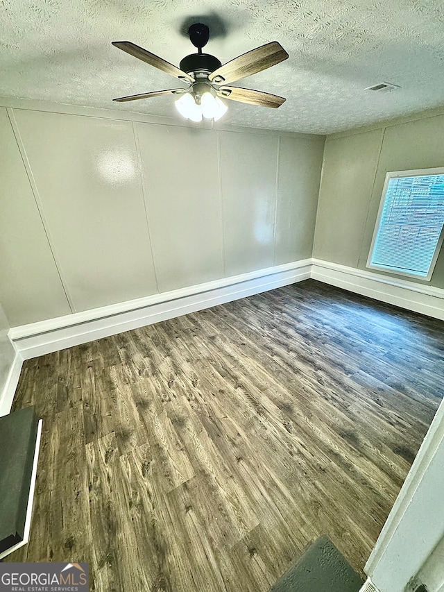 empty room with dark hardwood / wood-style floors, ceiling fan, and a textured ceiling