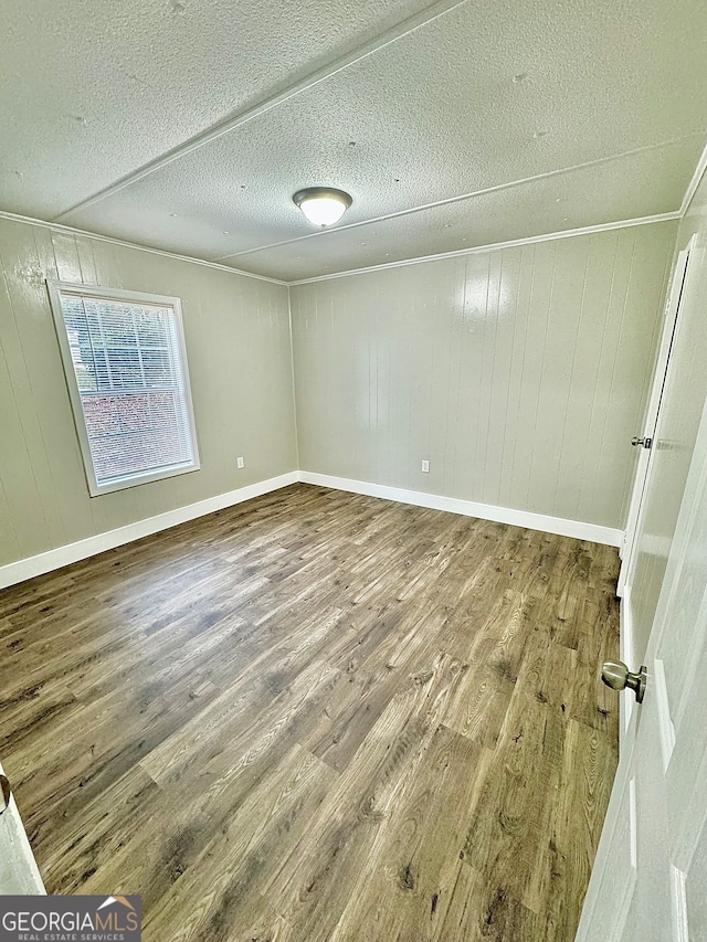 unfurnished room featuring wood-type flooring, a textured ceiling, and wood walls