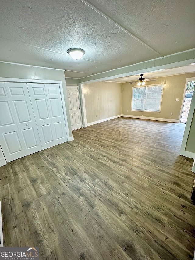 interior space with wood walls, wood-type flooring, a textured ceiling, and a closet