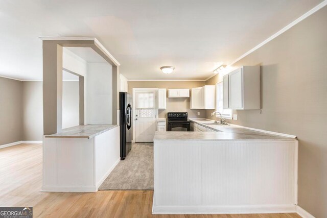 kitchen with kitchen peninsula, black range with electric cooktop, stainless steel fridge with ice dispenser, light hardwood / wood-style floors, and white cabinetry