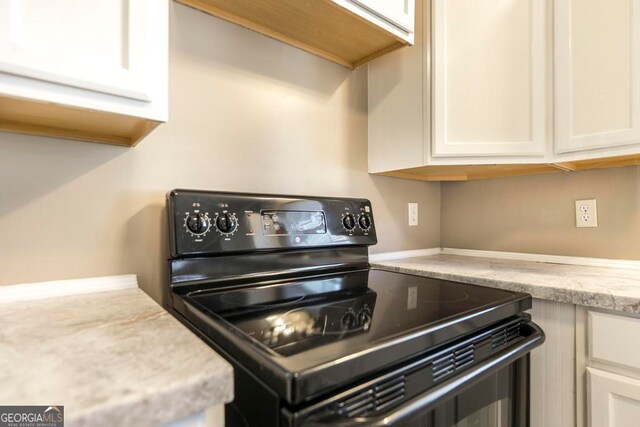 kitchen featuring white cabinetry, light stone countertops, and black / electric stove