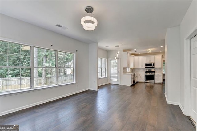 unfurnished living room featuring dark wood-type flooring, a chandelier, and sink