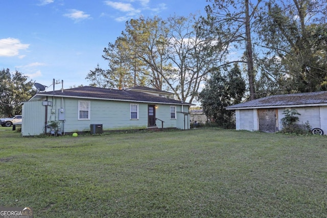 rear view of property featuring an outbuilding, a yard, and central AC