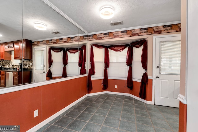 interior space featuring crown molding, a textured ceiling, and a wealth of natural light