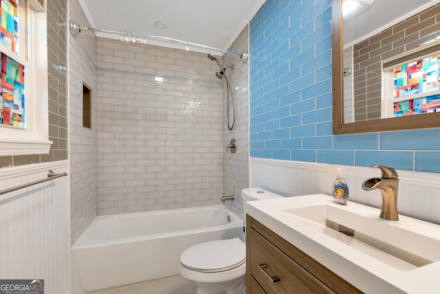 full bathroom featuring tiled shower / bath, vanity, toilet, and tile walls