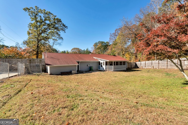 back of house featuring a lawn and a sunroom