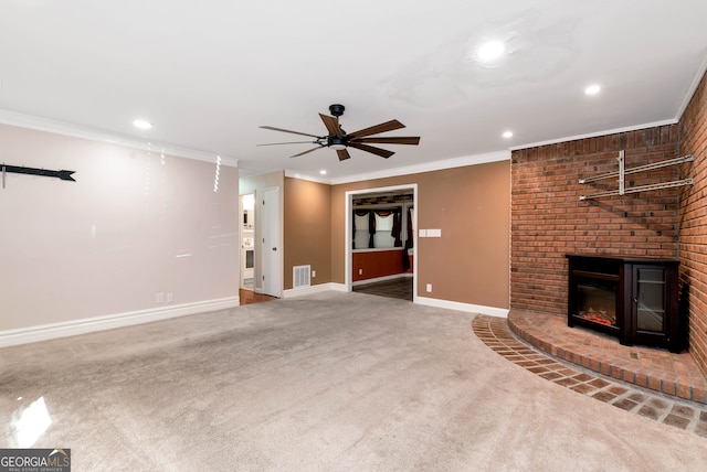 unfurnished living room with carpet flooring, ceiling fan, ornamental molding, and a brick fireplace